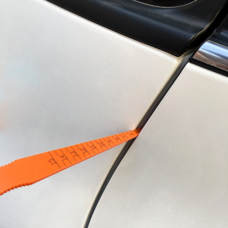 Orange gap gauge ruler along car body panel seam near black trim