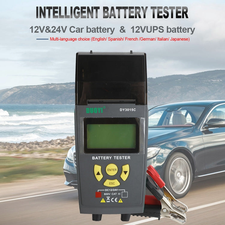 Car battery tester mounted outdoors with LCD screen and red/black clamp leads