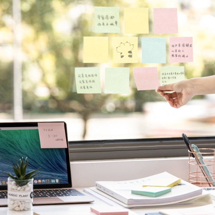 Hand placing colorful sticky notes on a window, desk notes ready to write