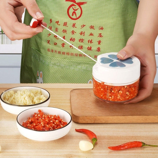 Manual mini garlic chopper with clear bowl and blue flower lid on kitchen board