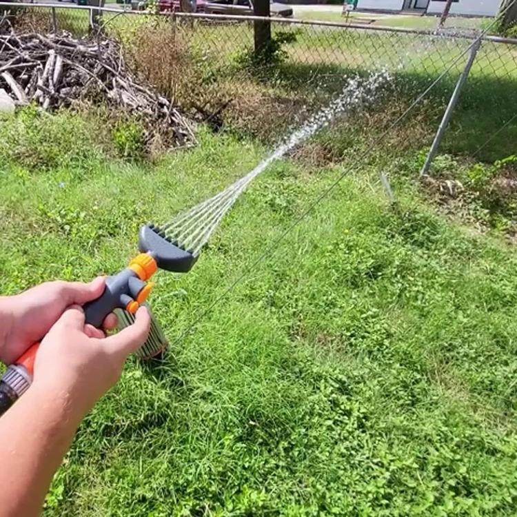 Handheld pool filter cleaning brush spraying water with black bristle head and orange fittings