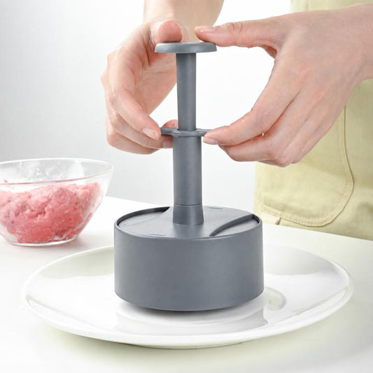 Grey round hamburger patty press with base cylinder and push handle held by hands