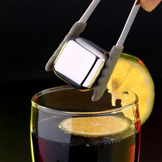 Reusable stainless steel ice cube with handle tongs, above a whiskey drink