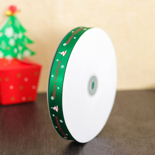 Green 'Merry Christmas' ribbon roll on white spool with decorative print