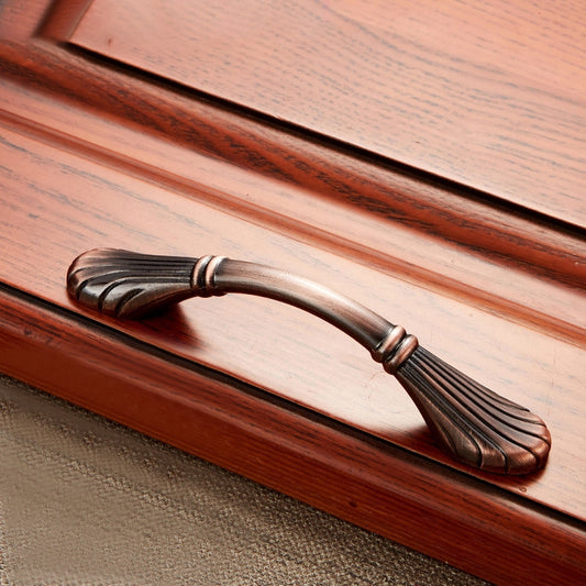 Wood cabinet handle with bronze arched grip and ribbed thumb rest