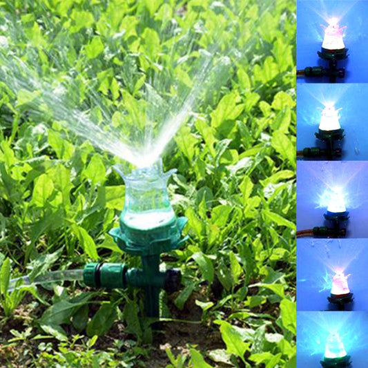 LED garden sprinkler with green stand, clear top, and water spray misting above grass