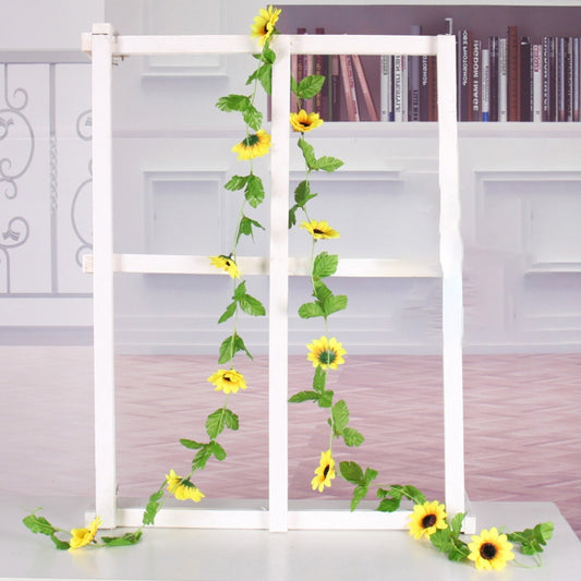 Artificial sunflower garland draped on white window frame, yellow blossoms with green leaves