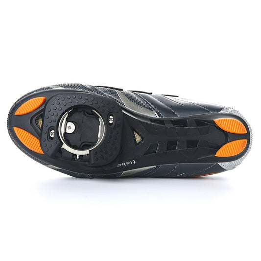 Underside of cycling shoe with black cleat cover and orange side accents
