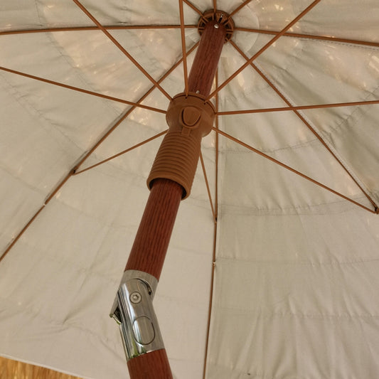 Beach umbrella pole and spokes with beige canopy underside and finial detail