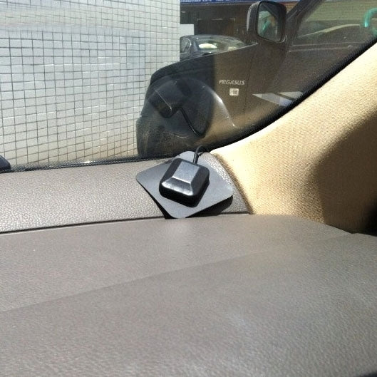 Active GPS antenna mounted on car dashboard with black puck and cable lead