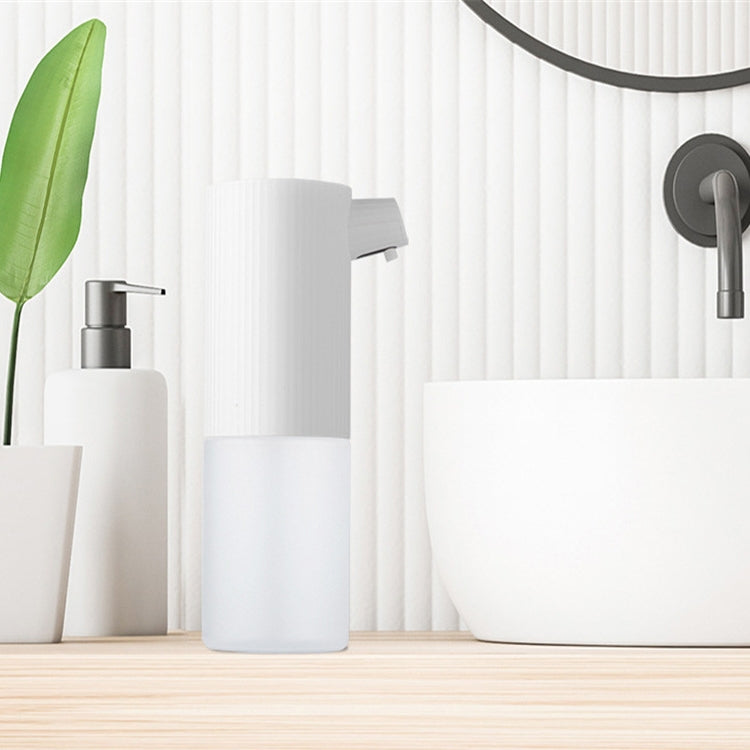 Automatic foam soap dispenser with ribbed white top and pump nozzle on a countertop