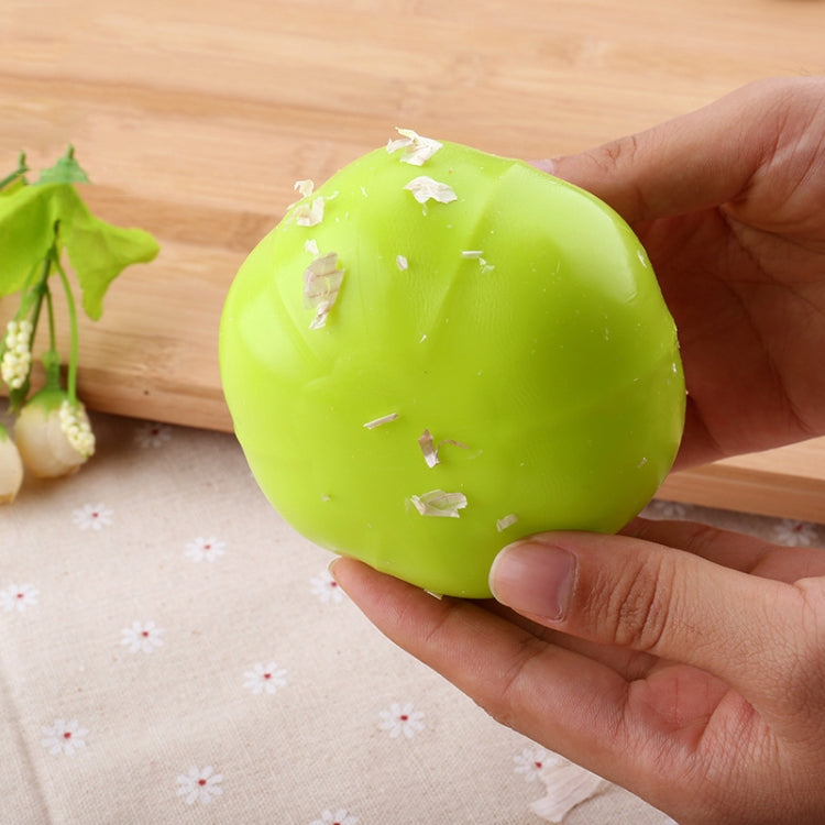 Lime green silicone garlic peeler with garlic peel residue after use.