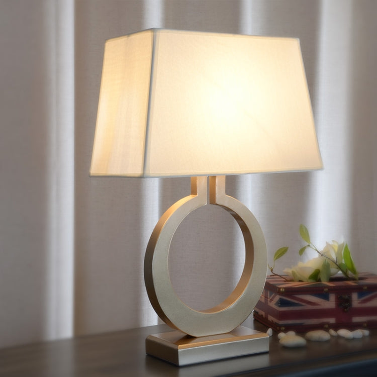 Warm-lit retro table lamp with oval ring base and beige fabric shade