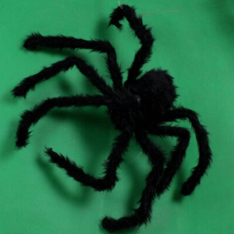 Black plush spider decoration with long fuzzy legs against a green background