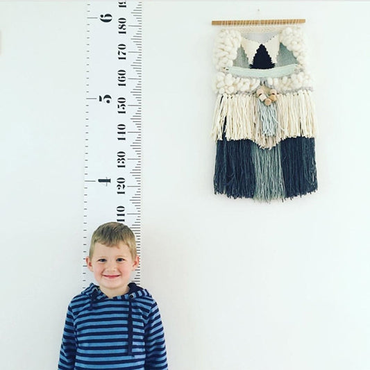 Kids height growth chart wall ruler with white tape and black numbers, wooden top