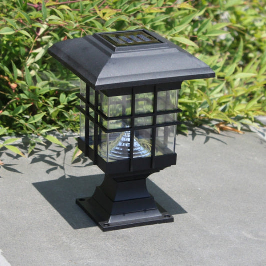 Black solar pillar garden light with glass lantern and grid panels on a walkway