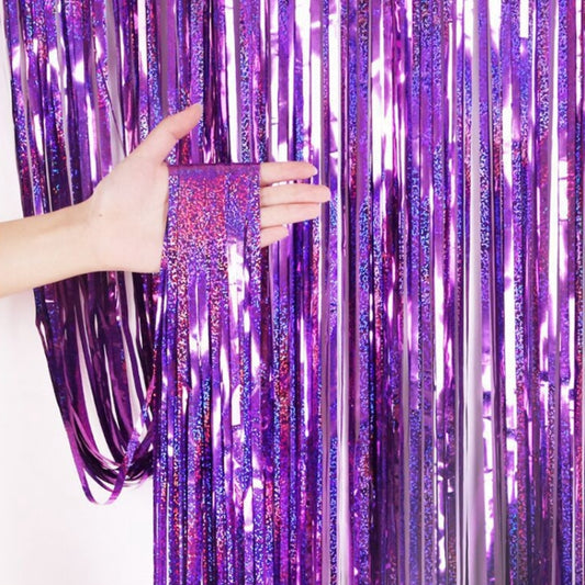 Purple holographic foil tinsel curtain with hanging strips, held in hand.