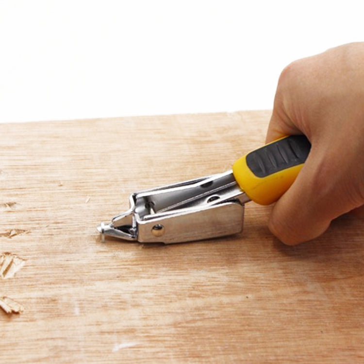 Hand uses nail remover tool on wood surface with yellow-and-black handle