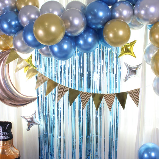 Blue, gold, and silver balloon arch with star-shaped foil balloons and blue fringe backdrop