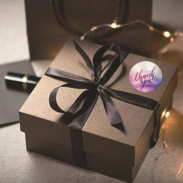 Decorative round "Thank you" sealing sticker on a gift box with ribbon