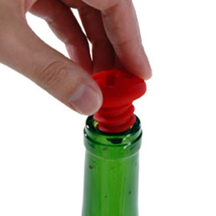 Hand pressing a red screw-style silicone bottle stopper onto a glass bottle