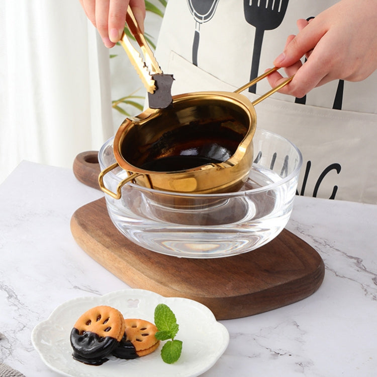 Gold stainless steel melting bowl on a glass base, with long handle and side loop grips