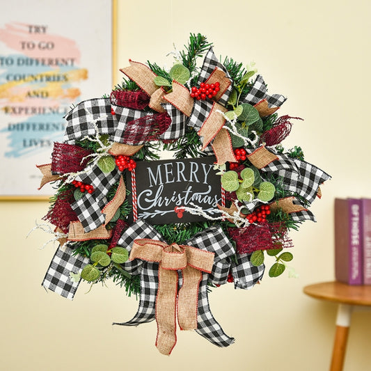Christmas wreath door decoration with green pine, plaid ribbons, red berries, and a “Merry Christmas” banner