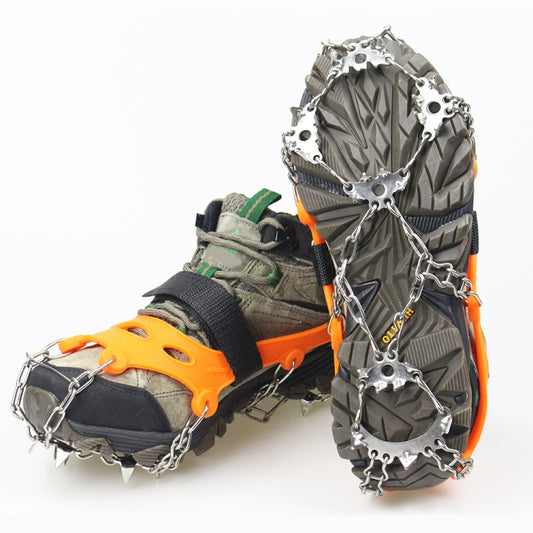 Orange ice traction crampons with steel spikes and chain straps on winter boots