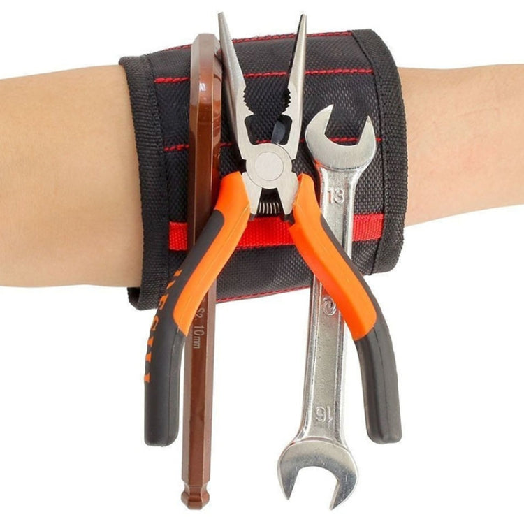 Magnetic wrist strap with red stitching holding tools; black strap with metal pliers