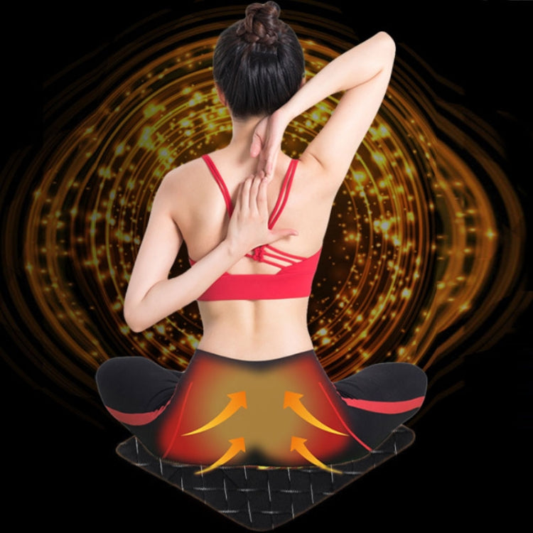 Black heating cushion pad placed under a seated person for warmth