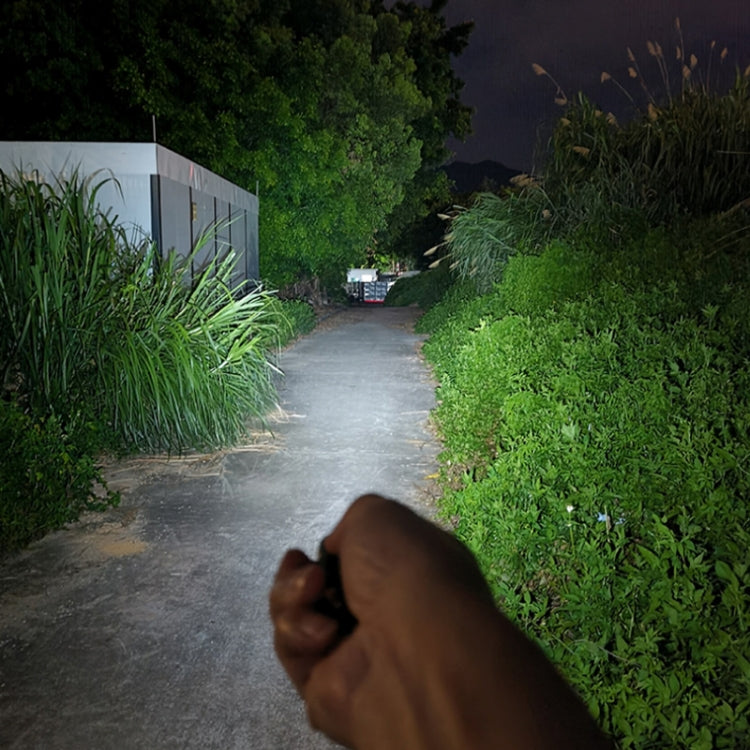 Mini keychain flashlight emitting a bright beam from a hand grip