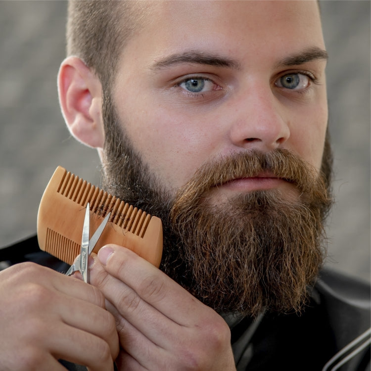 Wooden beard comb in hand grooming a full beard.