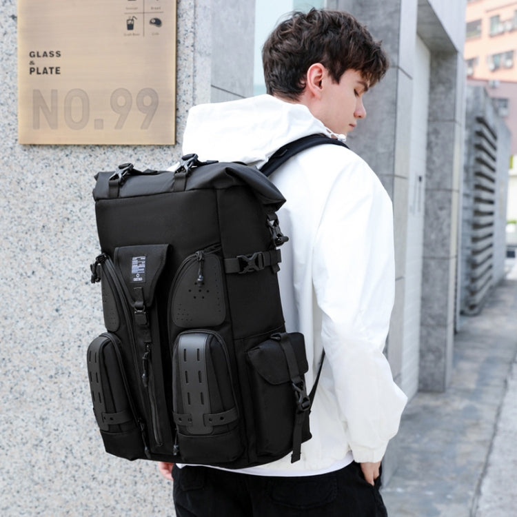 Black waterproof outdoor backpack worn by a person with front pockets and adjustable straps