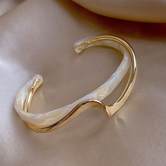 Gold-tone curved cuff bracelet with white shell-like inlay