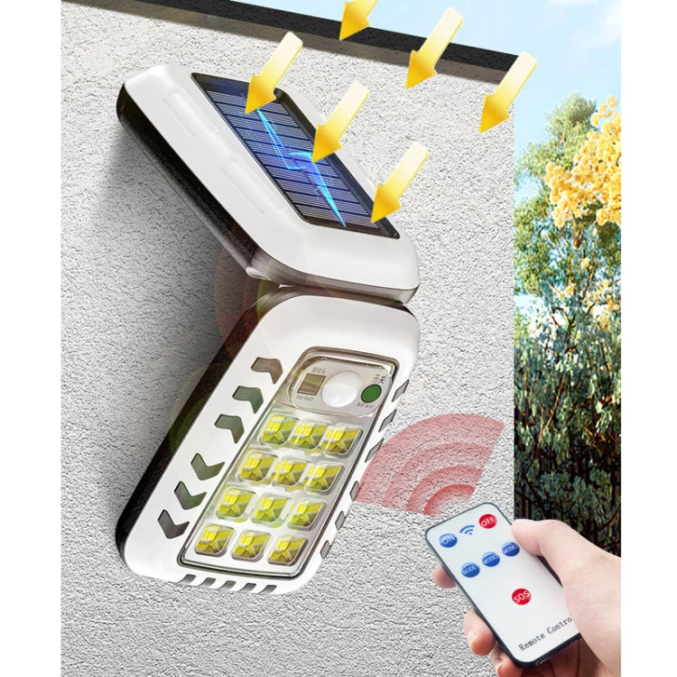 Solar wall street light mounted outdoors with illuminated LED panel and remote in hand