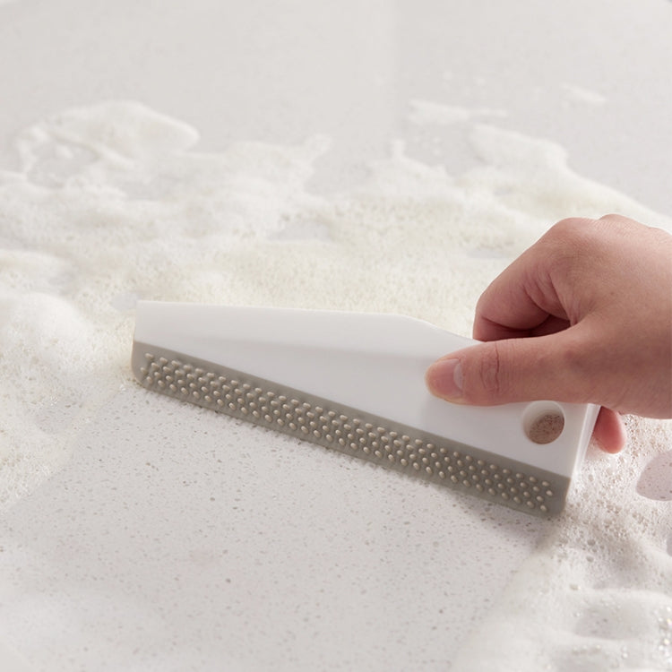 Manual cleaning scraper with perforated brush head wiping foamy sink surface