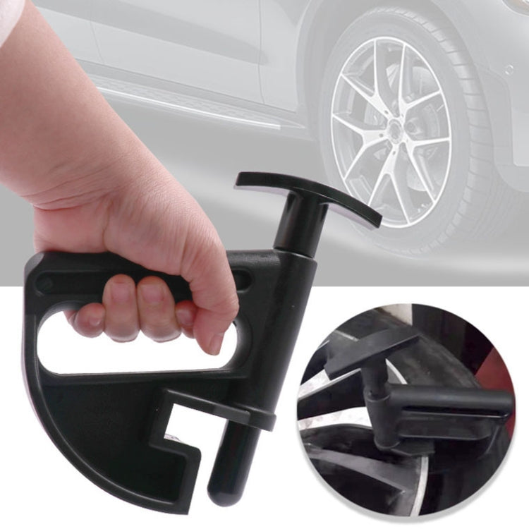 Hand holding black tire bead clamp tool near car wheel for bead seating