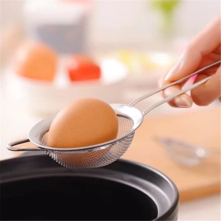 Stainless steel fine-mesh oil strainer holding an egg for draining