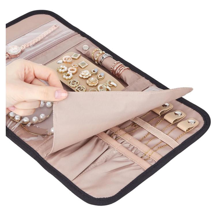 Pink faux-suede jewelry storage roll bag opened flat with ring and earring pockets