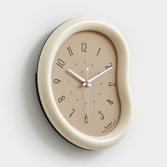 Beige wall clock with taupe face, minimalist hands and number markers, curved frame