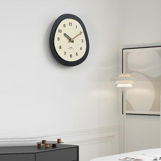 Modern oval wall clock with dark frame, cream face, and walnut wood hands