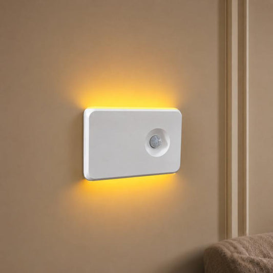 White motion sensor night light with glowing warm LED edge and round infrared lens