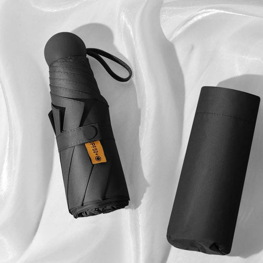 Black foldable capsule umbrella with matching strap, packed in compact sleeve.