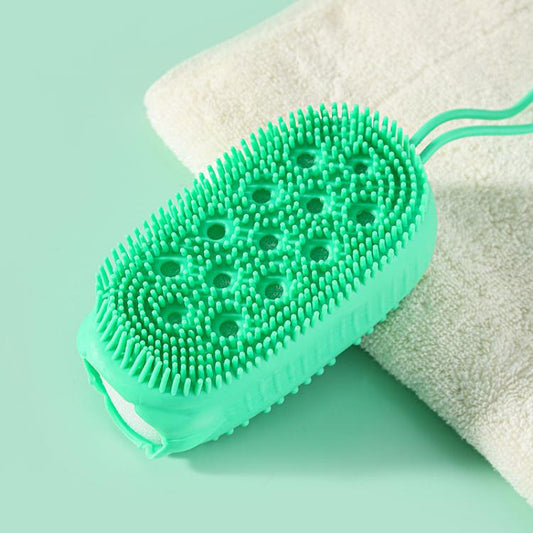 Green oval silicone body scrubber with small bristle tips on a bath sponge backing.