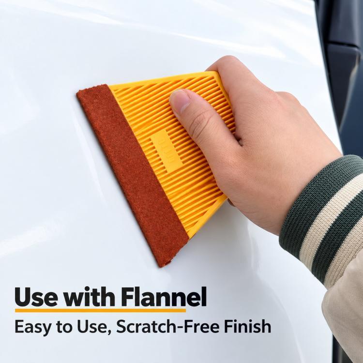 Orange window tinting squeegee with ribbed edge, held against a smooth surface.