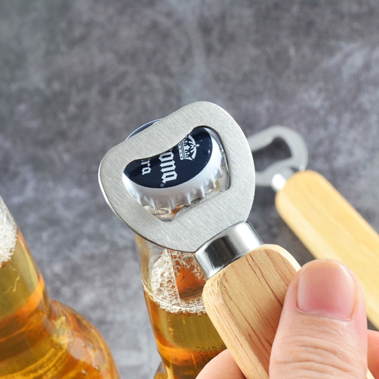 Stainless bottle opener with rubber wood handle prying a beer bottle cap