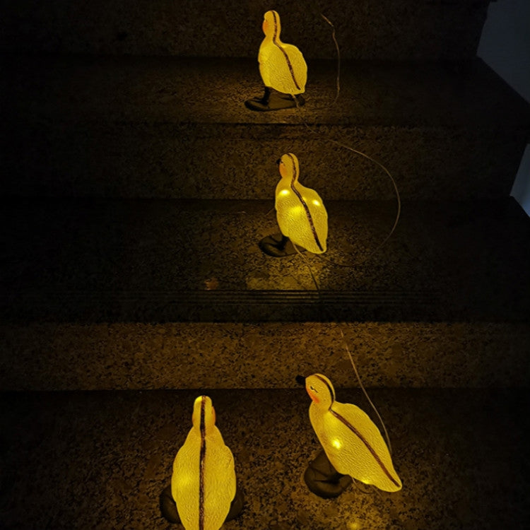 Glow-lit yellow duck solar stake lights with orange bases and connected wires