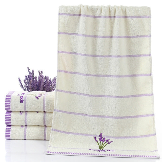 White cotton face towel with lavender horizontal stripes and embroidered sprig at bottom
