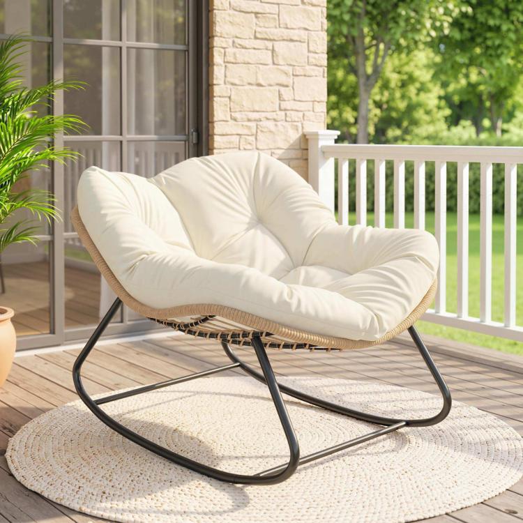 Oversized cream rocking chair with tufted cushion and woven rattan base on a porch