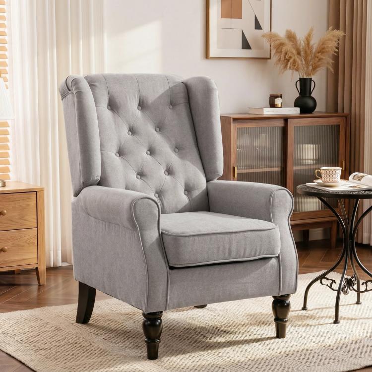 Gray upholstered reading chair with button-tufted back, rolled arms, and turned legs.
